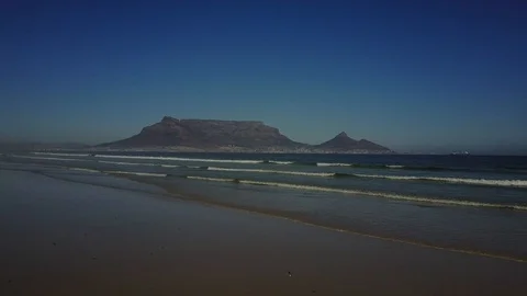 Beautiful Mountain Range Behind Waves Crashing On Beach [Drone Footage] Stock Footage 91040431