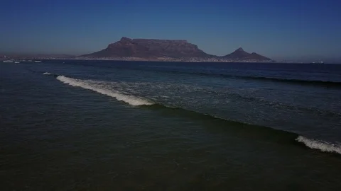 Beautiful Mountain Range Behind Waves Crashing On Beach [Drone Footage] Stock Footage 91040454