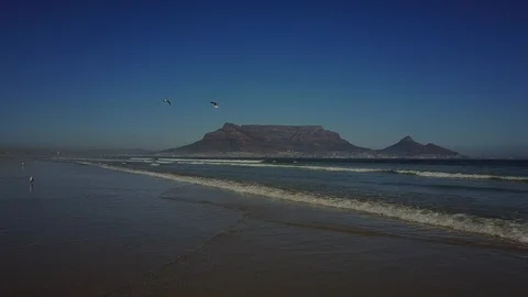 Beautiful Mountain Range Behind Waves Crashing On Beach [Drone Footage] Stock Footage 91040468