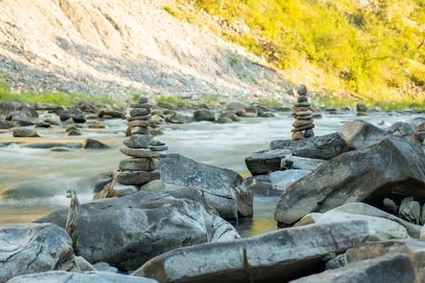 Beautiful mountain river with rapid current, two stone pyramids on foreground Stock Photos