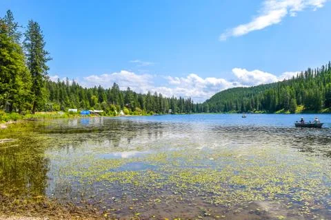 A beautiful mountain setting as two men fish from a small boat on a lake Stock Photos