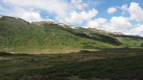 Beautiful Mountains with snow-capped peaks, covered with green forest. Stock Footage