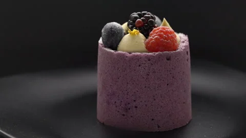 Beautiful mousse cake with fresh berries rotating on black plate Stock Footage 99251511