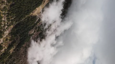 Beautiful movement of clouds over mountain forest slopes and snowy mountain peak Stock Footage 246984212