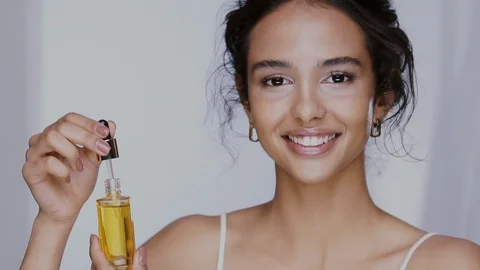 Beautiful mulatto with perfect skin dropping oil serum in front of her face and Stock Footage 123726898