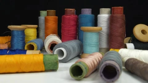 Beautiful multi-colored spools of thread lie on white table on black background Stock Footage 312071752