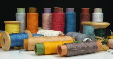 Beautiful multi-colored spools of thread lie on white table and rotates Stock Footage 316840026