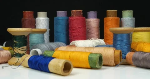 Beautiful multi-colored spools of thread lie on white table and rotates Stock Footage 321559664