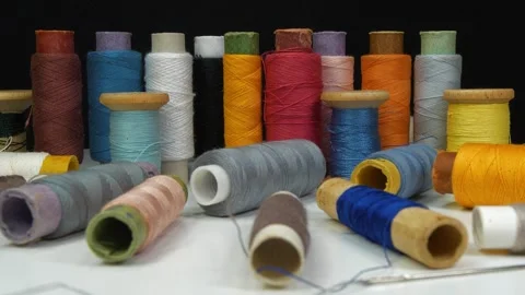 Beautiful multi-colored spools of thread lie on white table Stock Footage 321971277