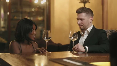 Beautiful multi ethnic couple drinking wine in bar in evening, pretty black Stock Footage 227112721