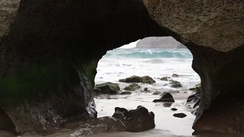 Beautiful Natural Arch Sea stack on sand beach coast with fog, moss, rocks Stock Footage 263739139
