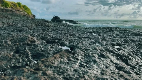 Beautiful natural background of black rocks and sea splashes in the distance at Stock Footage 169294515