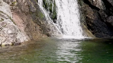 Beautiful nature view on a waterfall falling from a cliff into a clear lake Stock Footage 219487751