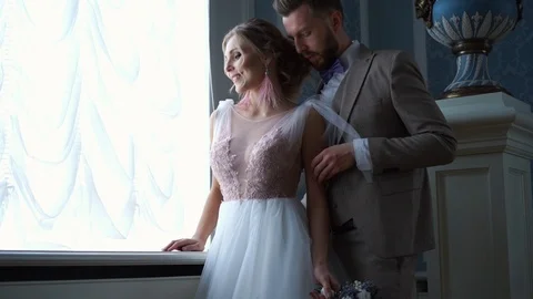 Beautiful newlywed couple posing in the chic expensive indoor by the window Video stock 102739732