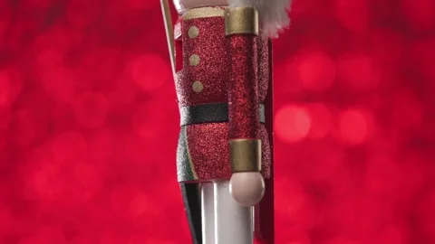 Beautiful Nutcracker is turning to face tha camera on bright red christmasy Stock Footage 321680373