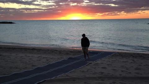 Beautiful Ocean scene with sun setting and silhouette of boy walking Stock Footage 140996456