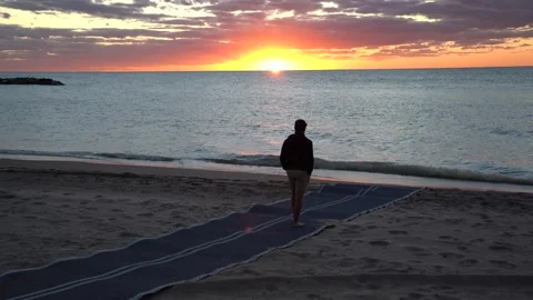 Beautiful Ocean scene with sun setting and silhouette of boy walking Stock Footage 140996574