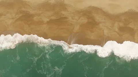 Beautiful ocean waves and splashes on a sandy beach in Nazar , Portugal. Aerial Stock Footage 80900098