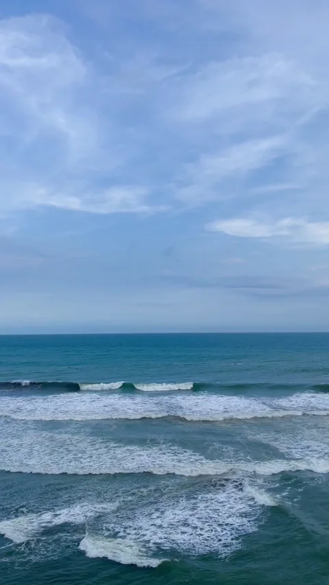 Beautiful Ocean Waves Crashing Under a Cloudy Blue Sky Stock Footage 340256951
