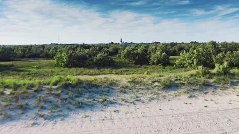 Beautiful old lighthouse on sand dune against blue sky with white clouds. Red Stock-Footage 132424943