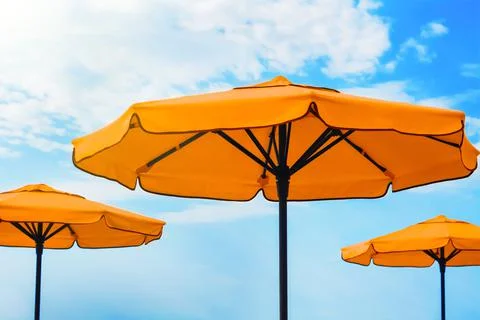 Beautiful orange beach umbrellas against blue sky Stock Photos