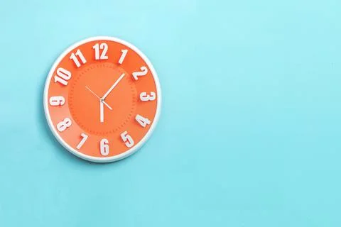 Beautiful Orange wall clock on blue background ,concept of Start the mornin.. Stock Photos