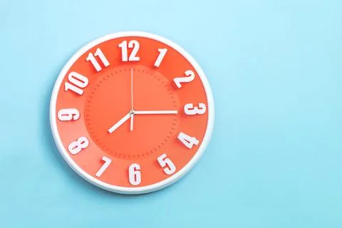 Beautiful Orange wall clock on blue background ,concept of Start the mornin.. Stock Photos