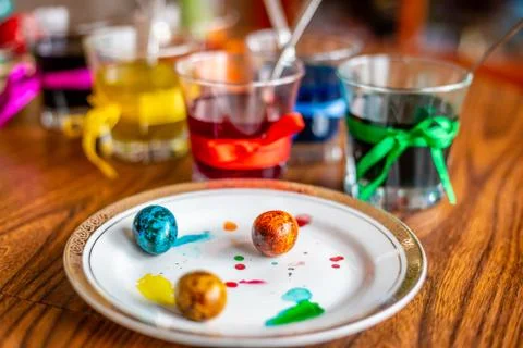 Beautiful painted easter egg, glasses with paints and plate with quail eggs. Stock Photos