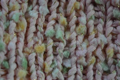 A beautiful patterned background is knitted from pink threads, colored inserts. Stock Photos