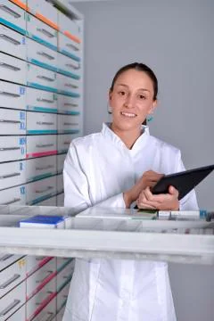 Beautiful pharmacist using notepad at the pharmacy Stock Photos
