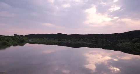 Beautiful pink orange sky reflected in rock pool on the beach at sunset. Stock Footage 131733169