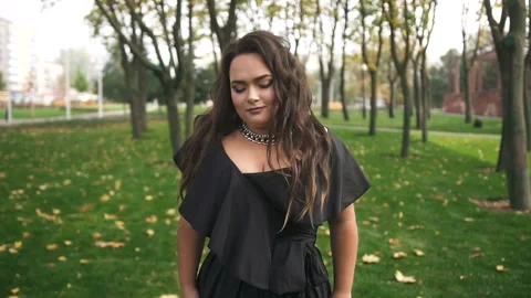 Beautiful plus size model in black long amazing dress at the park Stock Footage 110849992