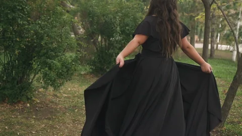 Beautiful plus size model in black long amazing dress at the park Stock Footage 110850253