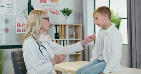 Beautiful positive friendly experienced blond female pediatrician checking boy's Stock Footage 156130074