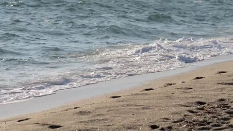Beautiful powerful waves splashing over golden shore with footprints Stock Footage 69086417