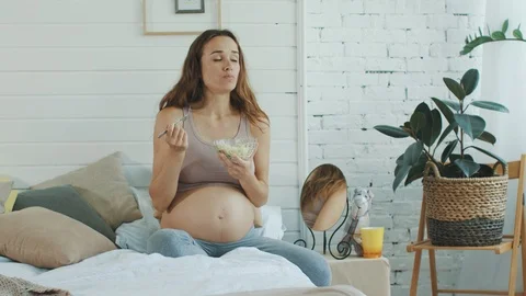 Beautiful pregnant woman eating vegetable salad bed. Belly mother holding bowl. Stock-Footage 123757299