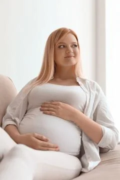 Beautiful pregnant woman resting on sofa at home Stock Photos