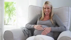 Young blond pregnant woman relaxing at home sitting on rocking