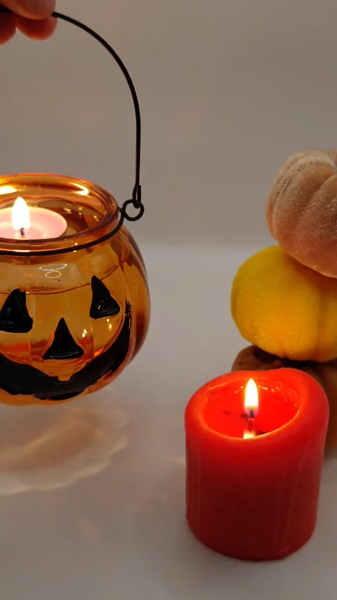 A beautiful pumpkin-shaped candle held in hand, close-up. Halloween holiday deco Stock Footage 319789660
