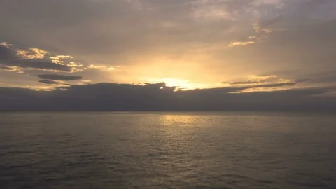 Beautiful push forward over calm ocean towards sunset, tilts down to sea Stock Footage 112696792
