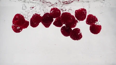 A beautiful raspberry falls into the water with bubbles in slow motion Stock Footage 93286326