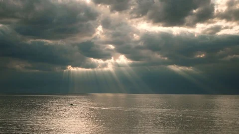 Beautiful rays of sun breaking through the clouds over the water sea or big lake Stock Footage 104443025