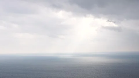 Beautiful rays of sun breaking through the clouds over calm sea ocean. Sunset Stock Footage 255198951