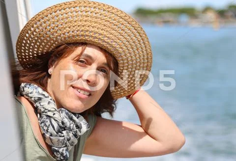 Beautiful real lady forty years old without makeup with straw hat on the ship Stock Photos