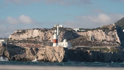 Beautiful red and white lighthouse on the rocks. Waves washing, crushing the Stock Footage 85285806