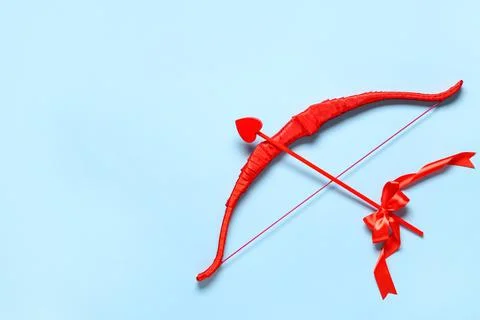 Beautiful red cupid's bow on blue background. Valentine's Day celebration Stock Photos