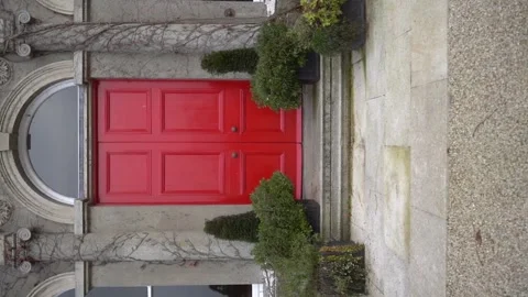 A beautiful red door with unique design amidst lush greenery Stock Footage 291173940