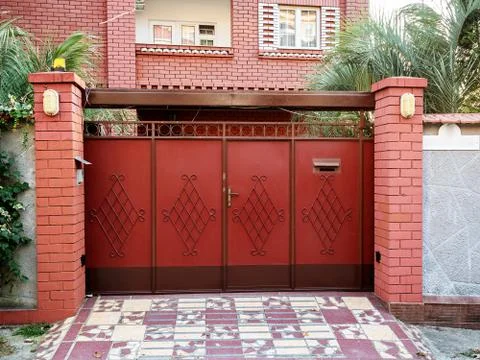 Beautiful red gates with forging elements on the background of the facade 写真素材
