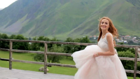 Beautiful red-haired bride dancing against the background of mountains. Slow Stock-Footage 87449565