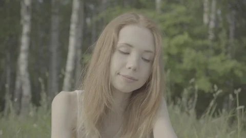 Beautiful red-haired girl sneezing from an allergy sniffing flowers Stock Footage 91258771